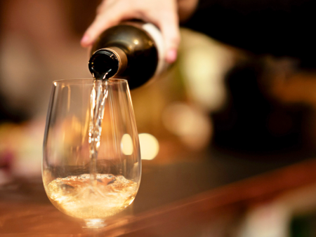 Photo of a hand pouring champagne into a wine glass by Dusty Bookhamer
