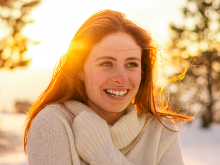 photo of a woman in a sweater with the sun shining behind her by Sally Grant