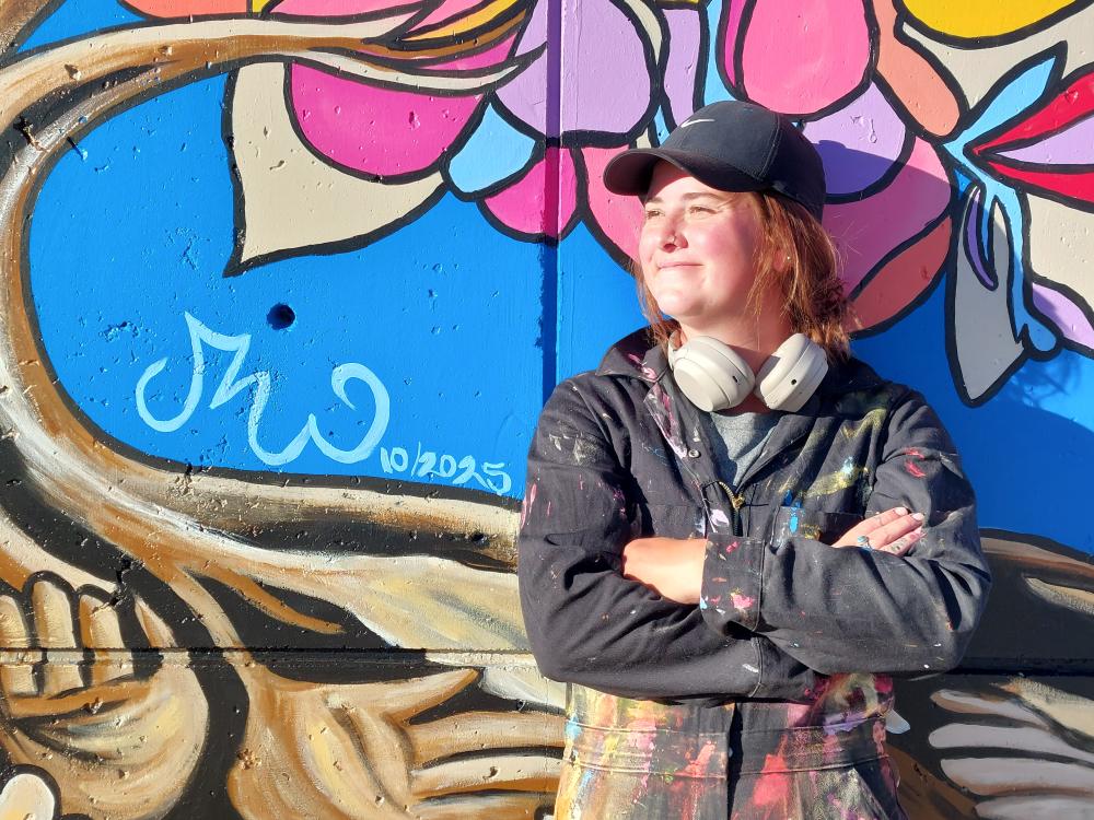 Shania Lauren Cissell in front of the mural at the Littleton Campus