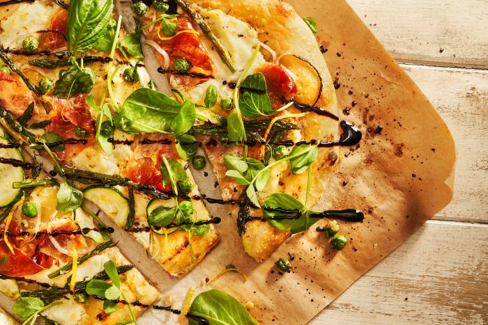 Close up of flatbread pizza with veggies on it.