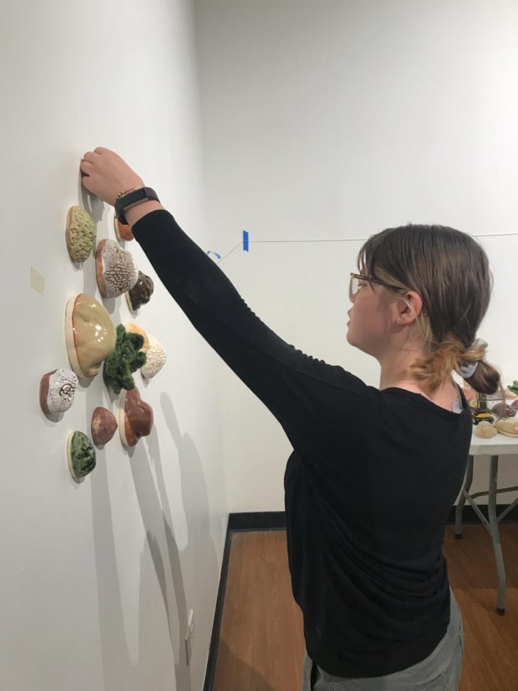 ACC student hanging a tactile art display at the Colorado Gallery of the Arts.