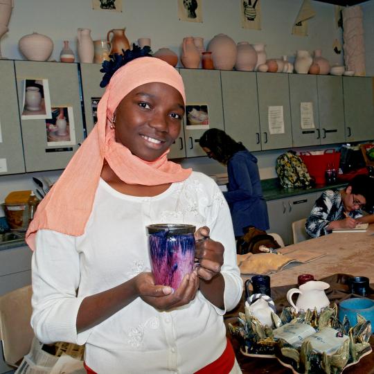 ACC ceramics student holding pottery.
