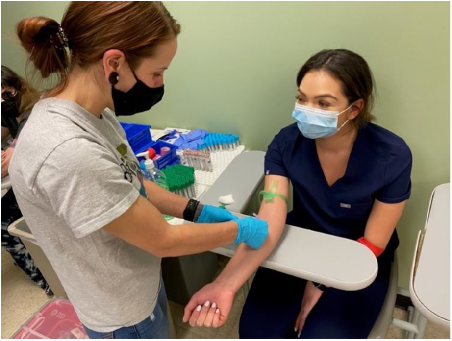 Two ACC Medical Assisting apprentices practice drawing blood on one another during class.