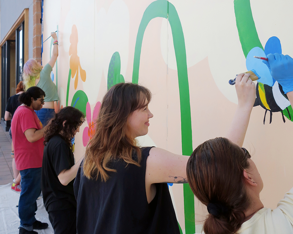 ACC Drawing 2 students painting a floral mural at Aspen Grove in Littleton, Colorado