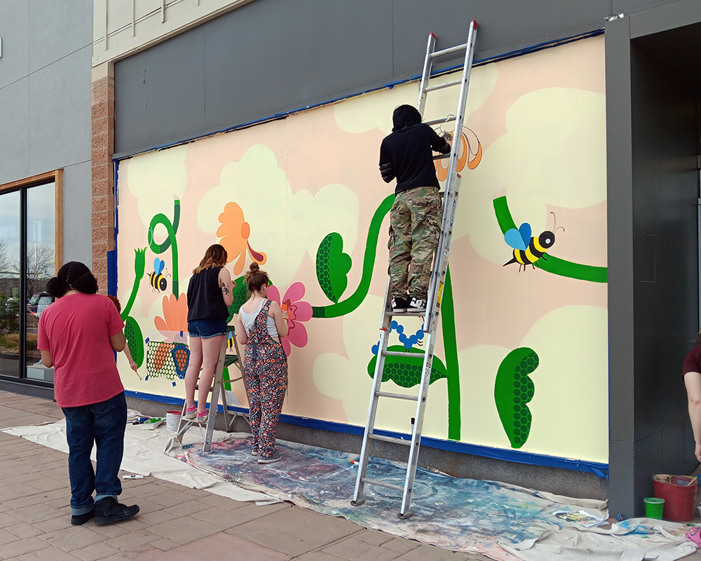ACC Drawing 2 students painting a floral mural at Aspen Grove in Littleton, Colorado