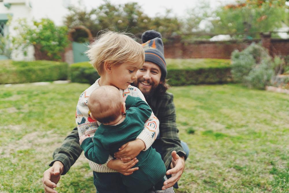 Portrait of father playing with sons outside.