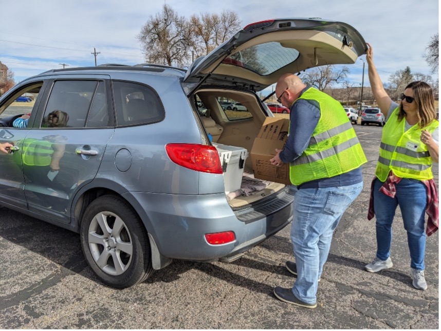 Volunteers loading food boxes into a car.