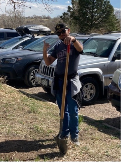 Volunteers standing with shovel and waving.