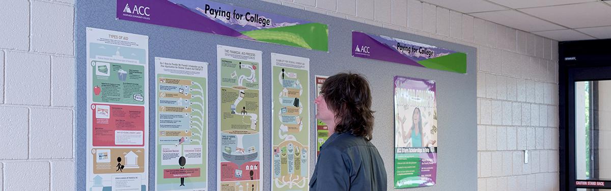 An Arapahoe Community College student studying a display board of the payment options and financial assistance available.