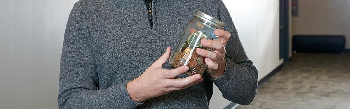 person holding a jar of money