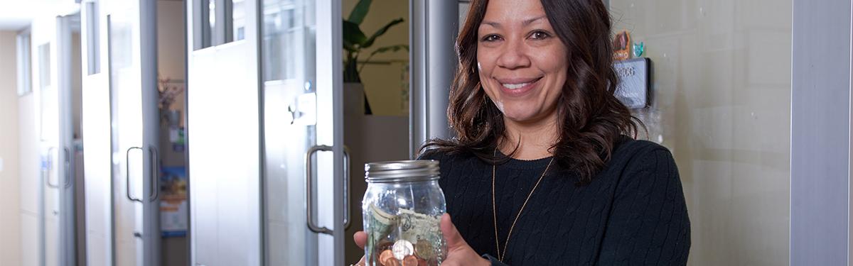 ACC employee holding a jar of money in the financial aid offices.