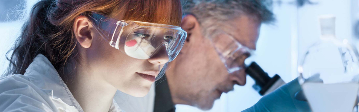 man and woman wearing safety googles using microscopes