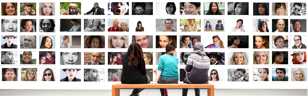 Three people sitting on a bench in front of a wall of photographs of diverse individuals and groups of people.