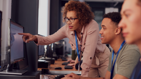 Computer technology instructor assisting students