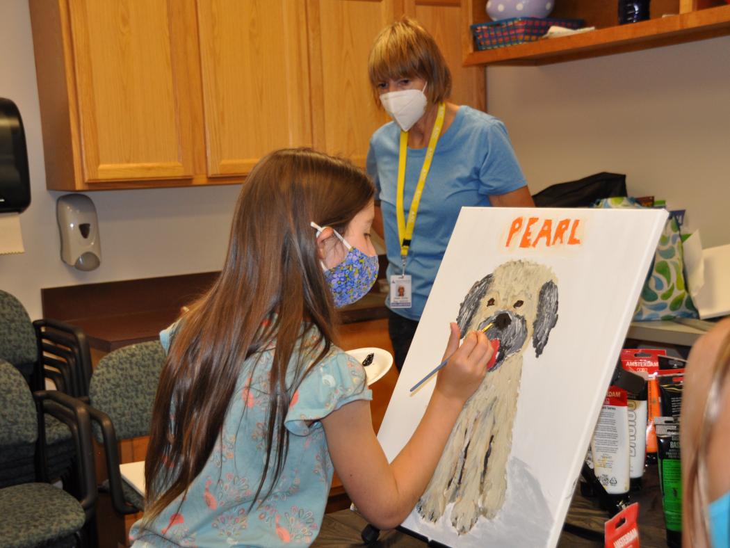 summer youth camp painting class with children painting on canvas.