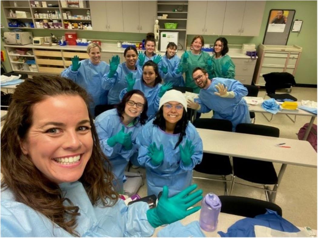 ACC Medical Assisting Apprentices in scrubs and gloves, pose for a picture during class.