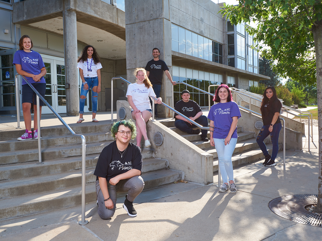 ACC students staggered on the stairs in front of the main entrance of the Littleton Campus main building.