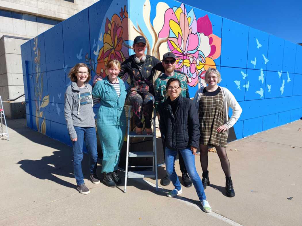 ACC students stand in front of completed mural: Roots of Learning, Wings of Growth, at the Littleton Campus.