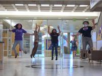 ACC students jumping in the air next to the Welcome Center at the Littleton Campus.