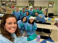 ACC Medical Assisting Apprentices in scrubs and gloves, pose for a picture during class.