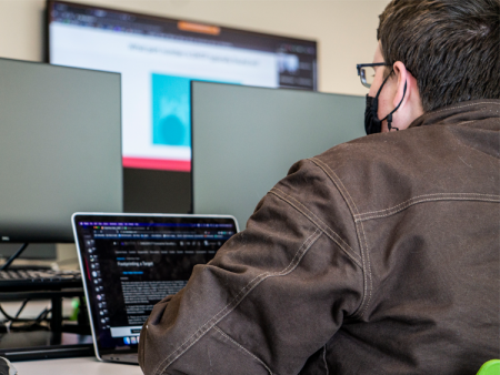 Secure software development AAS student in class at Arapahoe Community College's Sturm Collaboration Campus in front of computer.