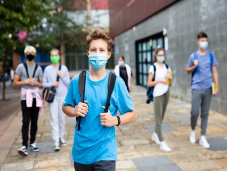 Children in masks outside of a school building.