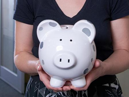 ACC employee holding a piggy bank in the Financial Aid office at the Littleton Campus.