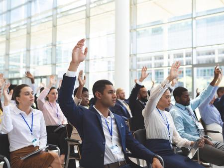 Event with people sitting and raising their hands in participation.