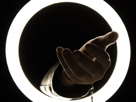 Hand reaching through circle of light (photo by Kailey Barnes)