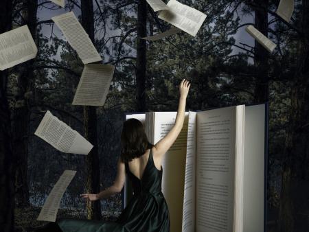 Woman in front of book with pages flying in forest (photo by Meagan Harkin)