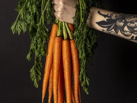 Hand holding a bunch of carrots (photo by Mercedes Peterson)