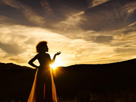 Woman standing silhouetted by sunset (photo by Peggy Tio)