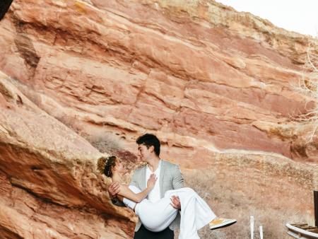 Woman in white being held by man in suit at Red Rocks in Colorado. Photo by Destiny Aukerman, ACC photography student