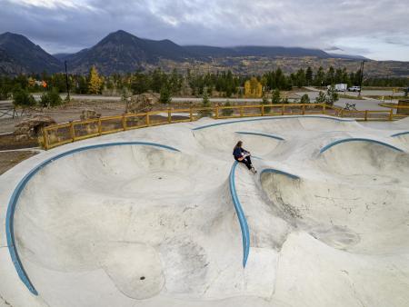 Woman sitting in the middle of an empty skate park holding skateboard. Photo by Nick Palmer, ACC photography student