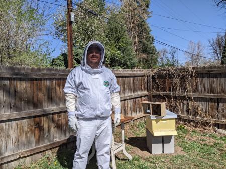 Luke Curtis, ACC Beekeeping student in beekeeper gear in front of beehive.