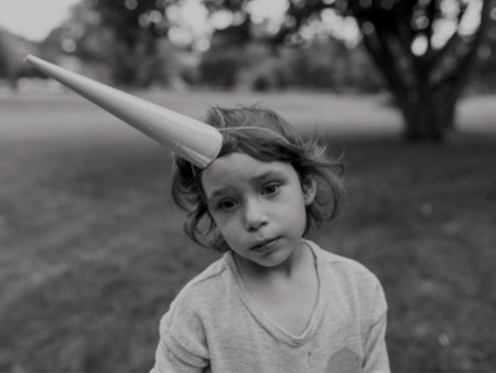 photo of child wearing long pointy hat with a sad expression - photo by Mary Schulte