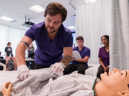 ACC Nurse Aide (CNA) students work with manikin while classmates watch at the Sturm Collaboration Campus at Castle Rock.