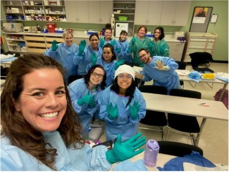 ACC Medical Assisting Apprentices in scrubs and gloves, pose for a picture during class.