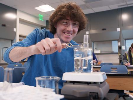 A student dips a test tub with a clear liquid inside clear liquid in a beaker and observes the reaction.