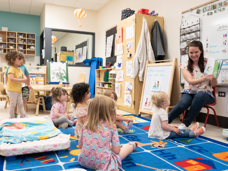 Children sitting on rug for story time with their teacher 