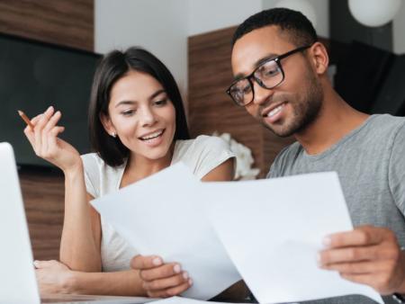 Man and woman reviewing documents and a computer.