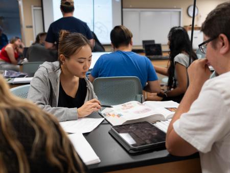 Students reviewing books in an ACC biology class at the Littleton Campus.