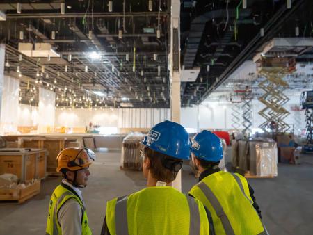 ACC students wearing construction helmets and safety vests in a warehouse. 