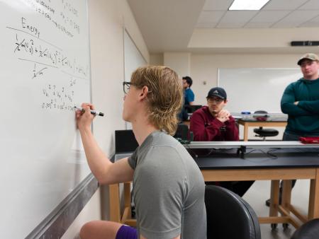 ACC student completing physics problem on a white board in a physics class at ACC's Littleton Campus.