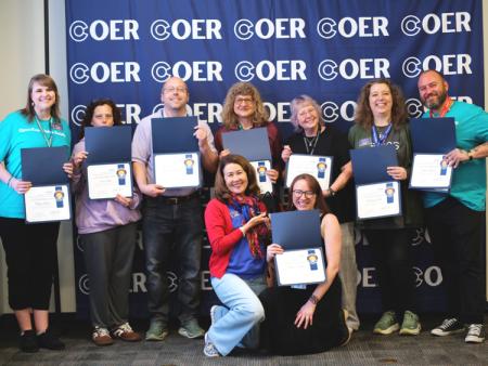 Members of ACC's OER team holding awards in front of Colorado OER logo wall