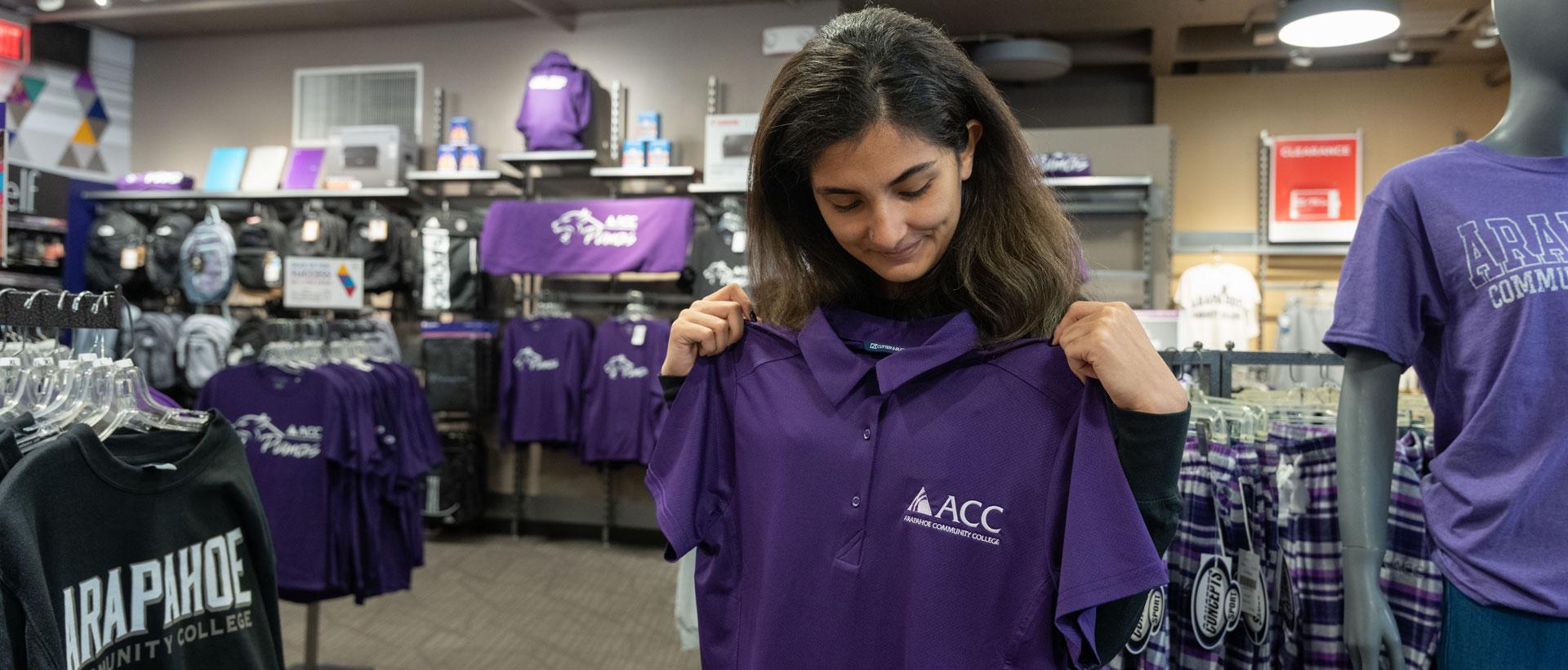 A student looking at an ACC shirt at the Littleton Campus Store.