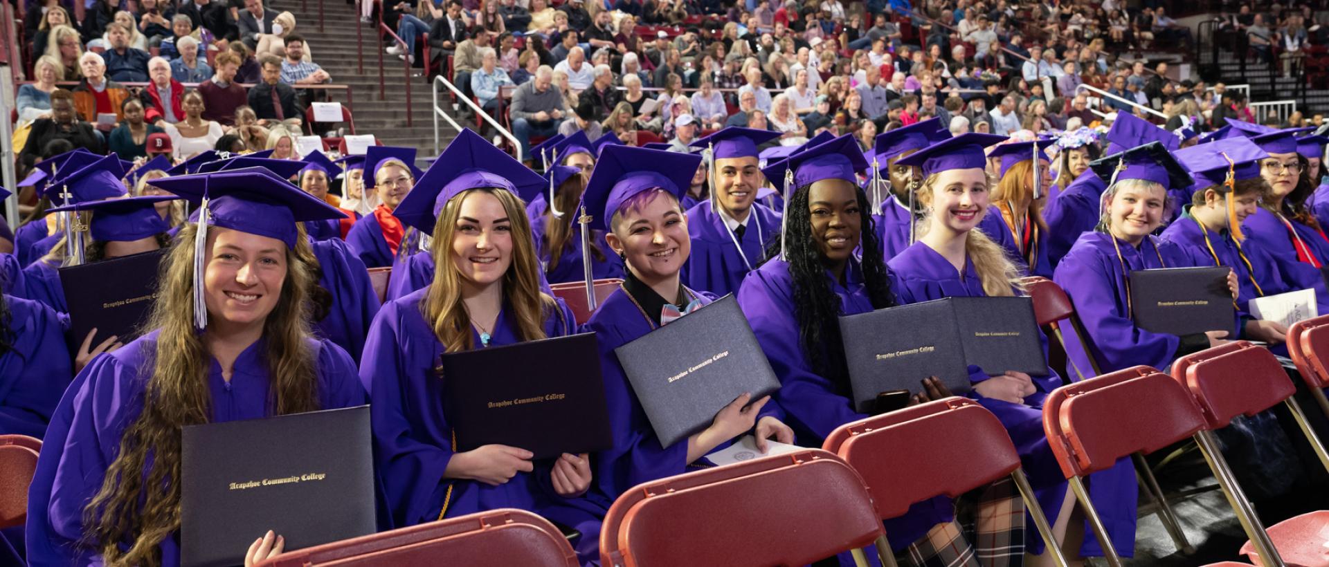 ACC graduates holding their diplomas during commencement at Magness Arena (DU).