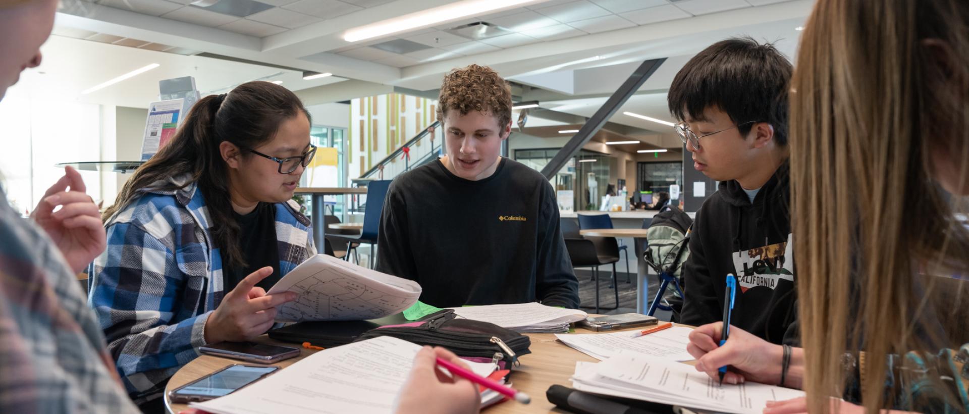 ACC students studying around a table in the student lounge at Sturm Collaboration Campus at Castle Rock.