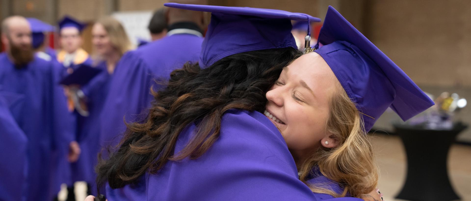 ACC students embrace at commencement at DU. 
