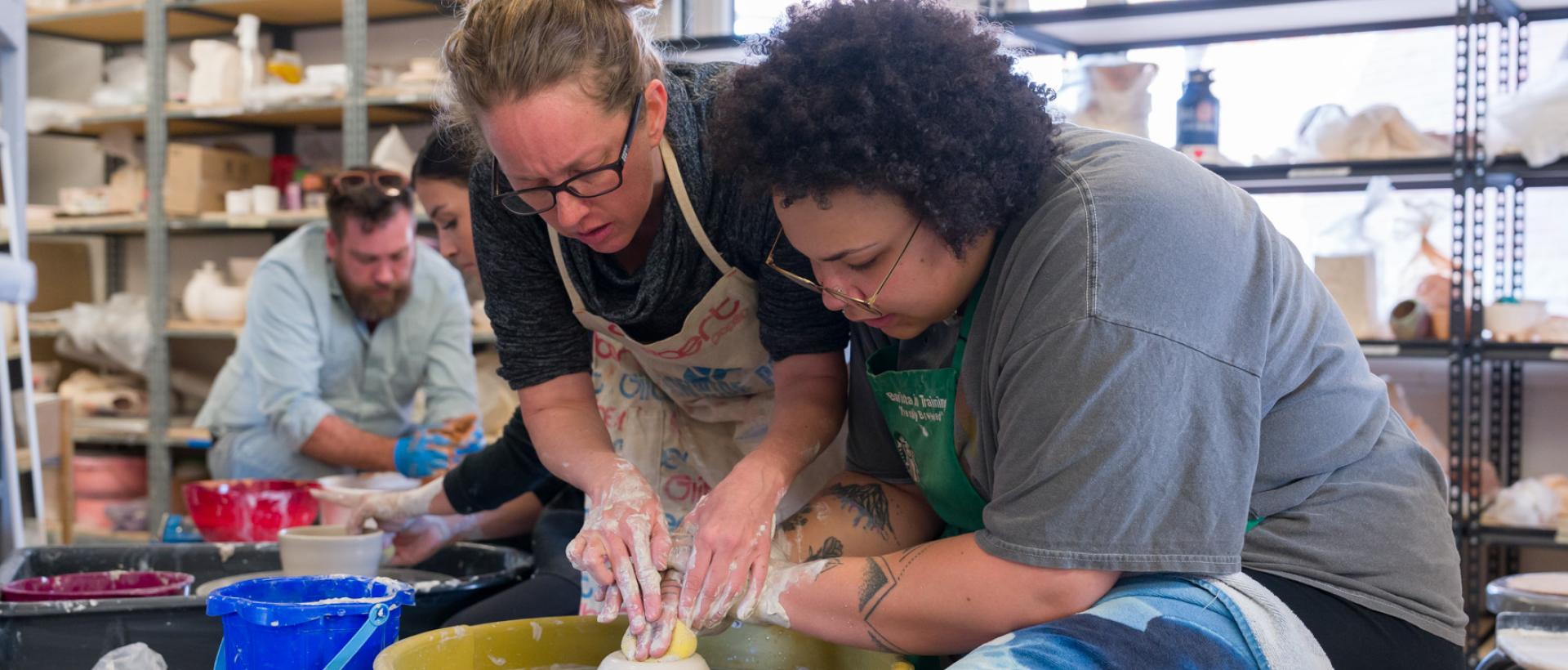 ACC faculty member helping student at the pottery wheel in the Art & Design Center at ACC's Littleton Campus.